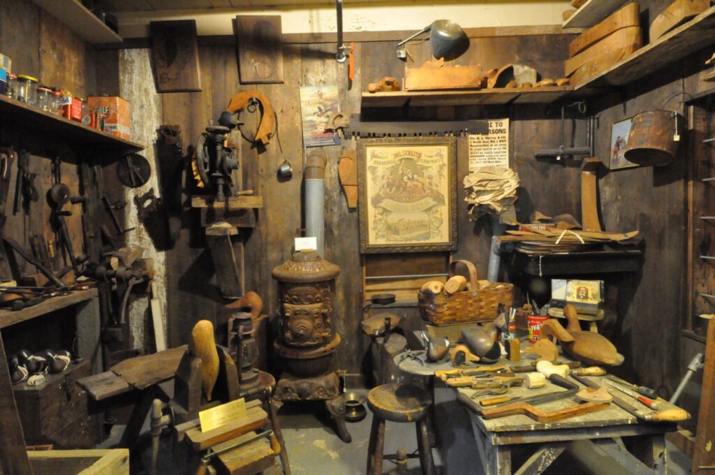A photo of the Decoy Carver's Shop in the Upper Bay Museum. There is a small stove, a bunch of decoy parts, and painting supplies.